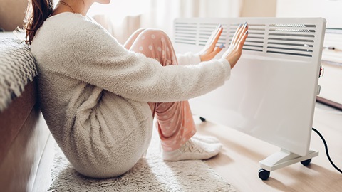 calefacción - mujer calentadose con calefactor eléctrico